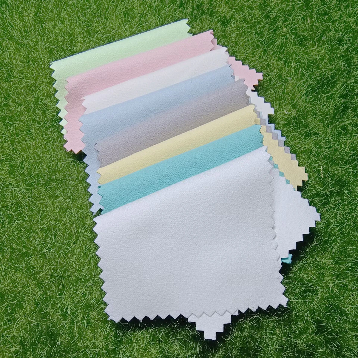 Assorted 6.5 x 10 cm rectangular silver polishing cloths displayed on green grass